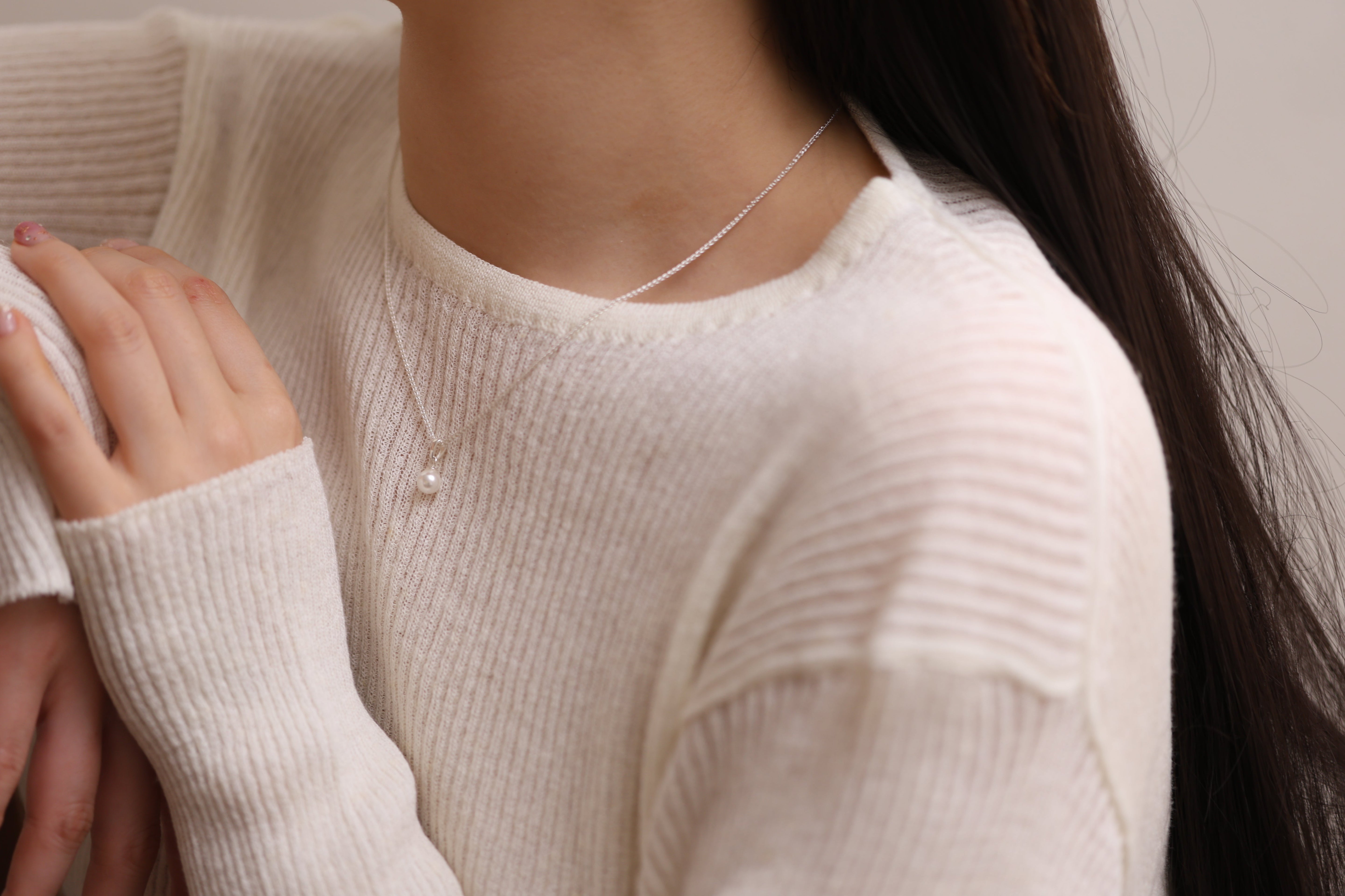 A woman wearing a delicate freshwater pearl pendant necklace from Nabilondon, perfect for Mother’s Day. The dainty design adds a touch of elegance and sophistication.